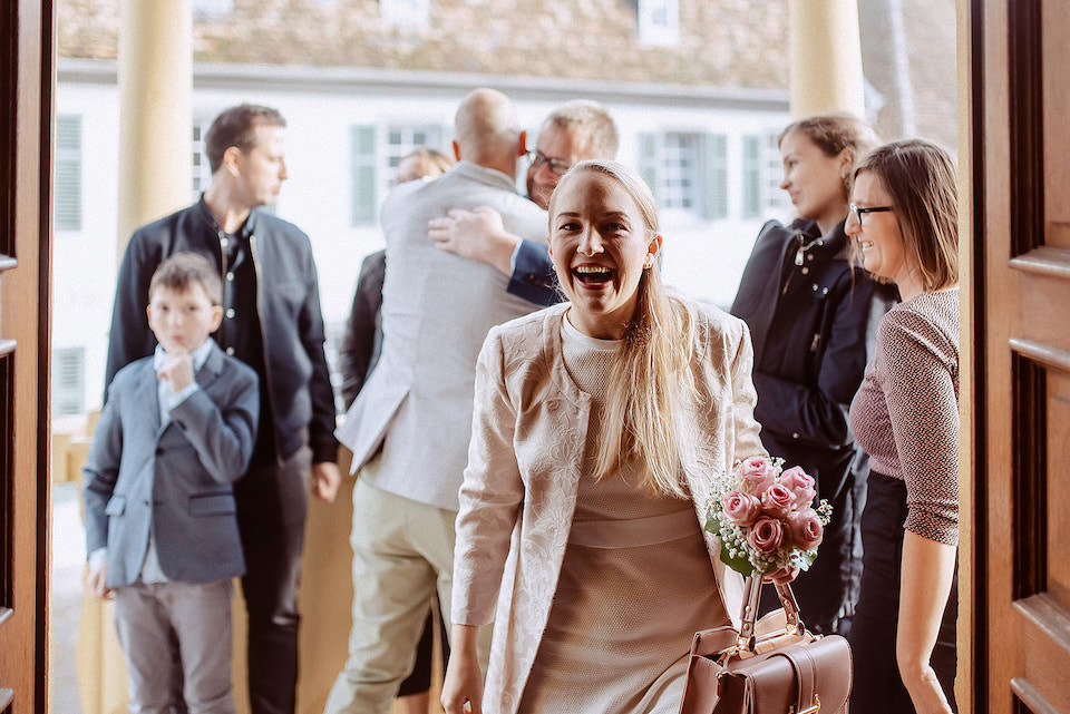 Braut begrüßt ihre Gäste, während sie das Standesamt in Deidesheim betritt