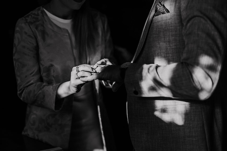 Braut steckt seiner Frau den Hochzeitsring an den Finger während ihrer standesamtlichen Hochzeit