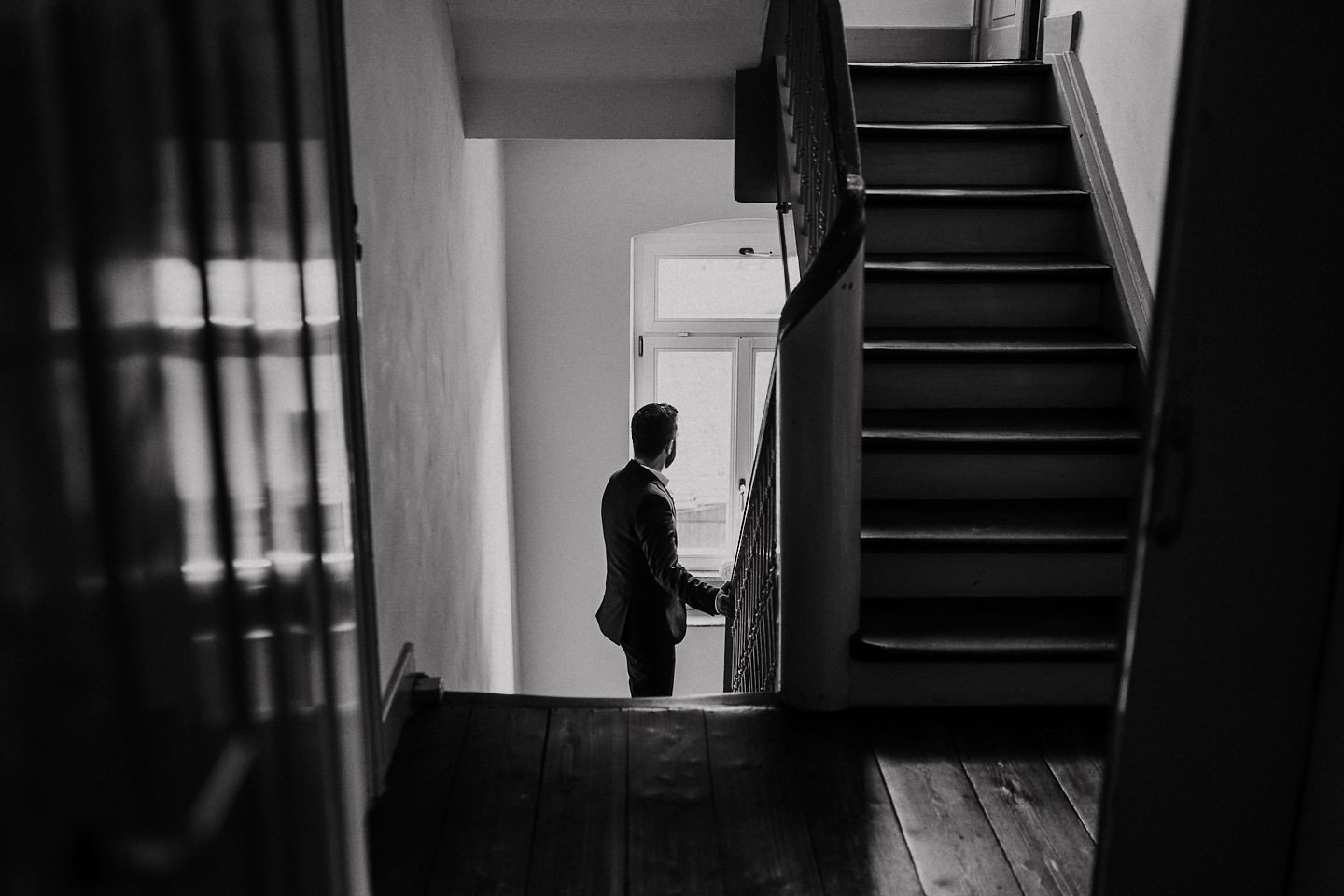 Bräutigam schaut aus dem Fenster während er im Treppenhaus steht
