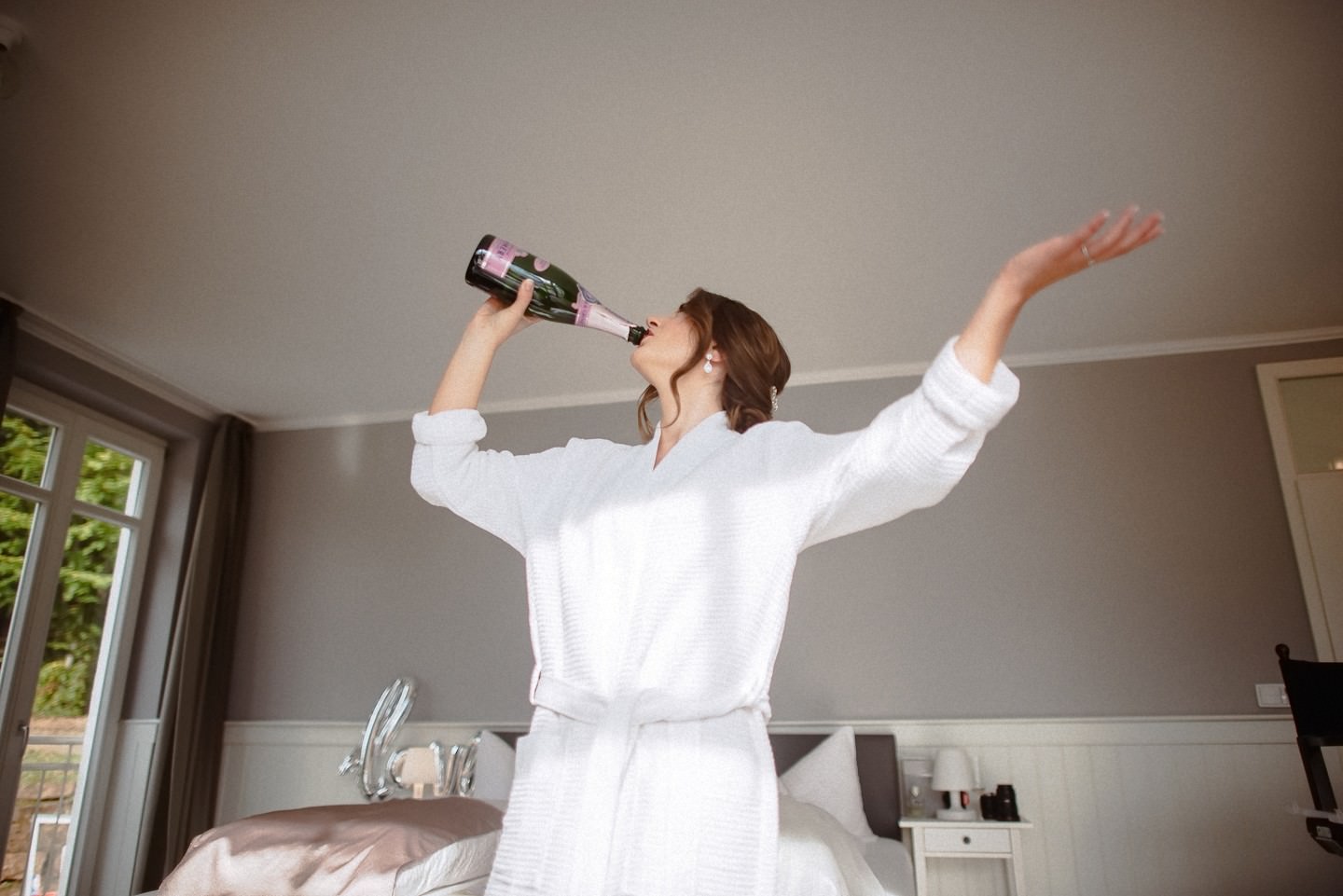 Braut trinkt Sekt aus der Flasche beim Getting Ready bei der Hochzeit auf dem hohen Darsberg