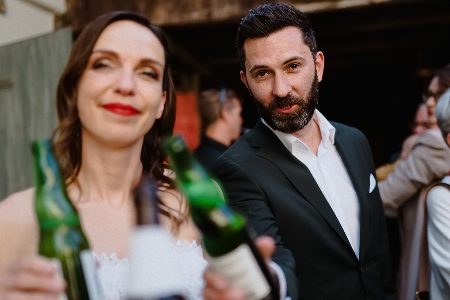 Hochzeitspaar stößt mit dem Fotografen mit Bier an