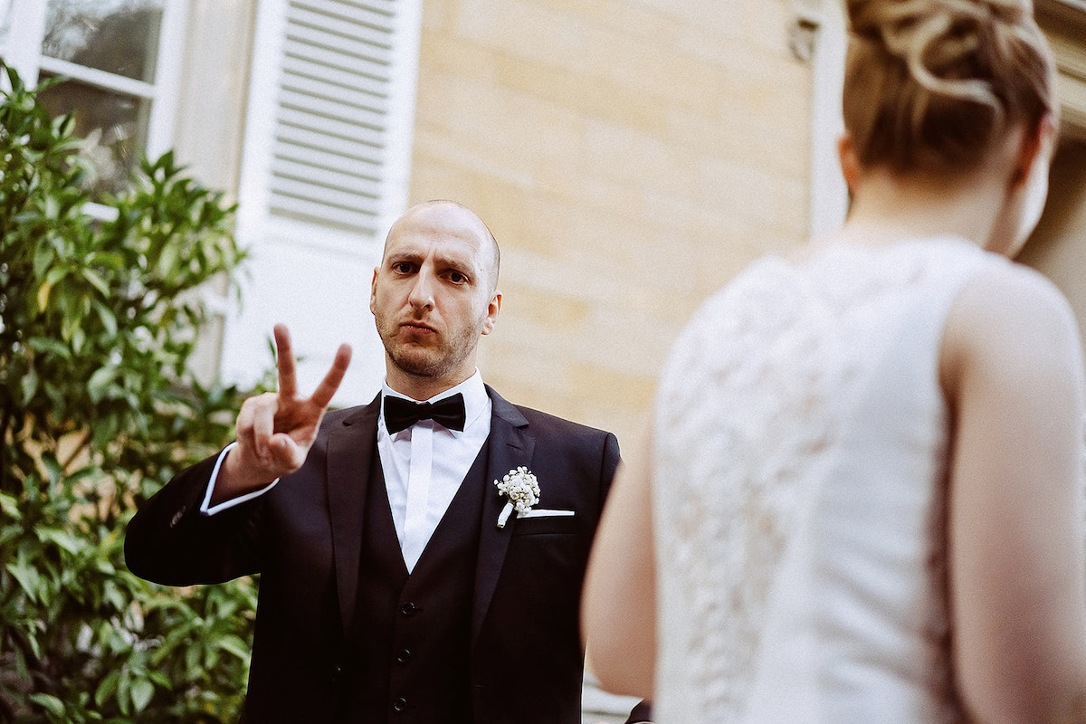 Bräutigam zeigt ein Peace Zeichen bei seiner Hochzeit bei Weingut von Winning