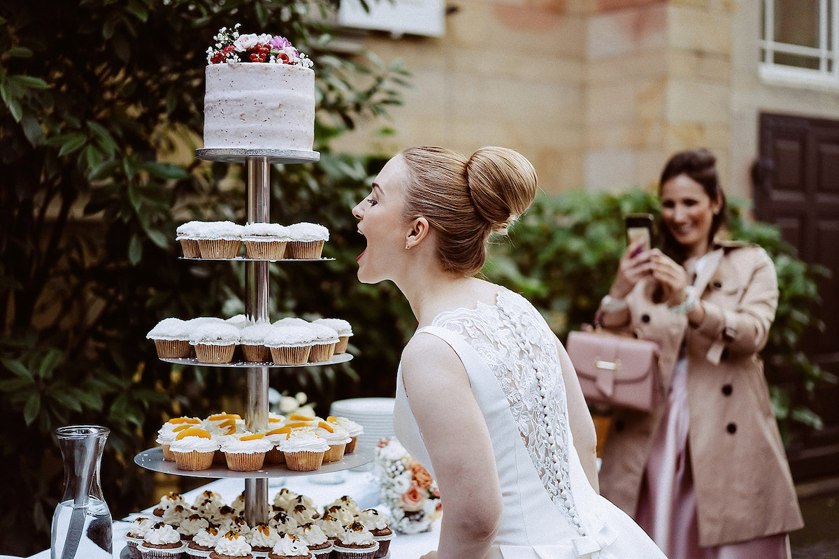 Braut beißt in einen Cupcake bei ihrer Hochzeit bei Weingut von Winning in Deidesheim