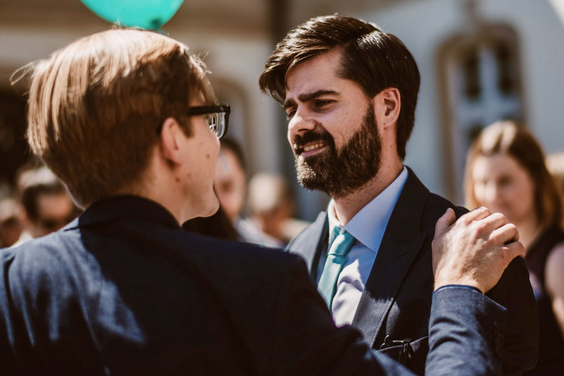 Der Bräutigam umarmt einen älteren Mann mit Brille in einem herzlichen Gratulations-Moment.