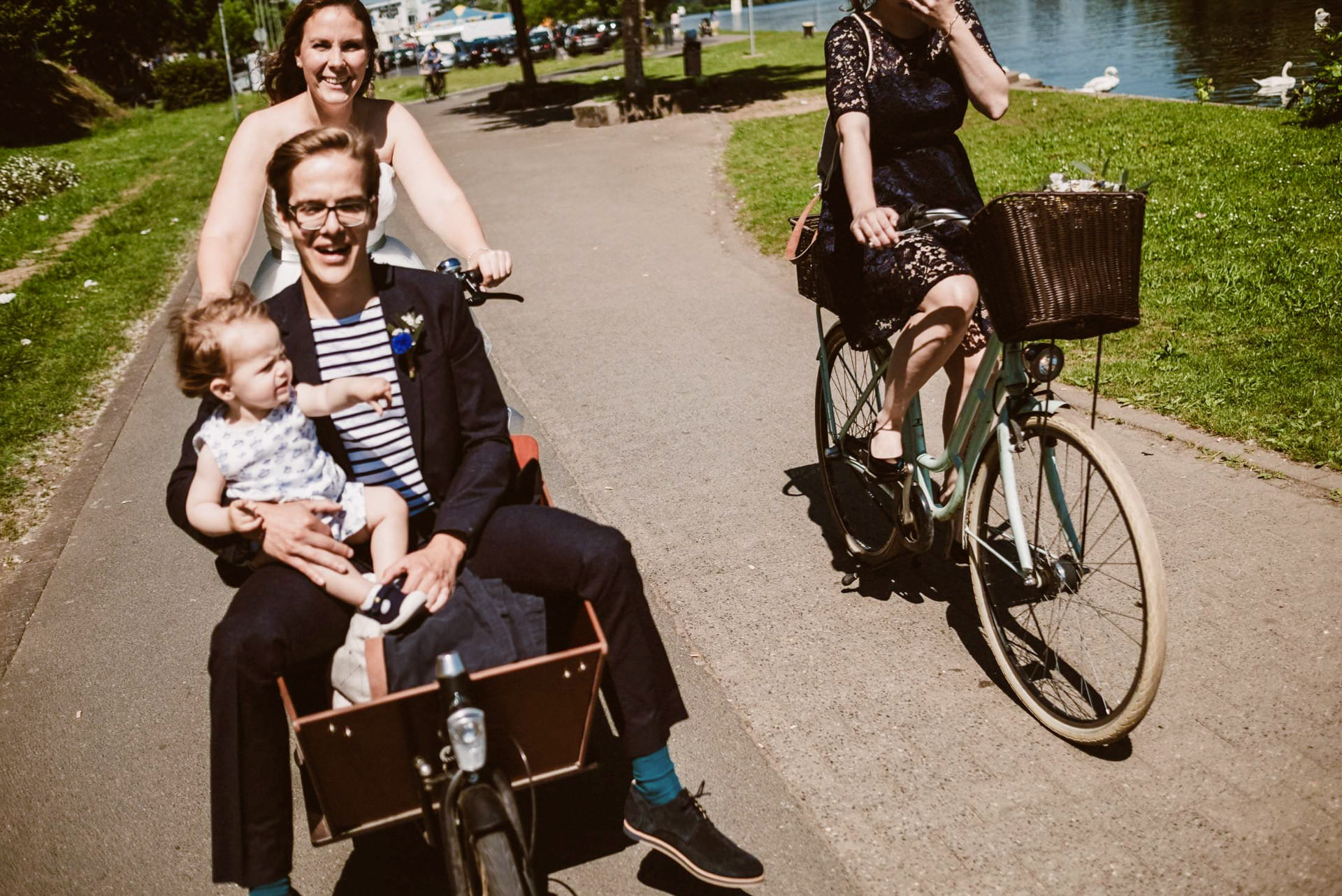 Das Brautpaar posiert stolz auf dem beladenen Lastenfahrrad in der Stadt.