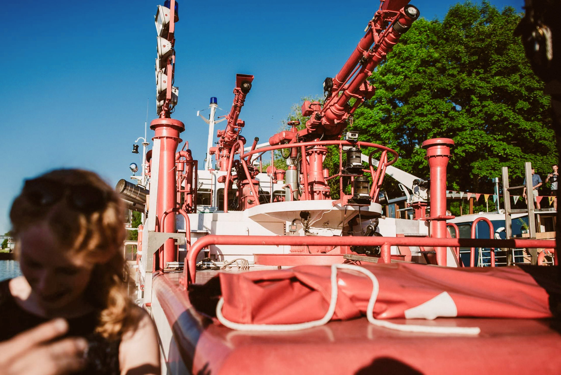 Das rote Löschboot sprüht beeindruckend Wasserfontänen neben dem Schiff.