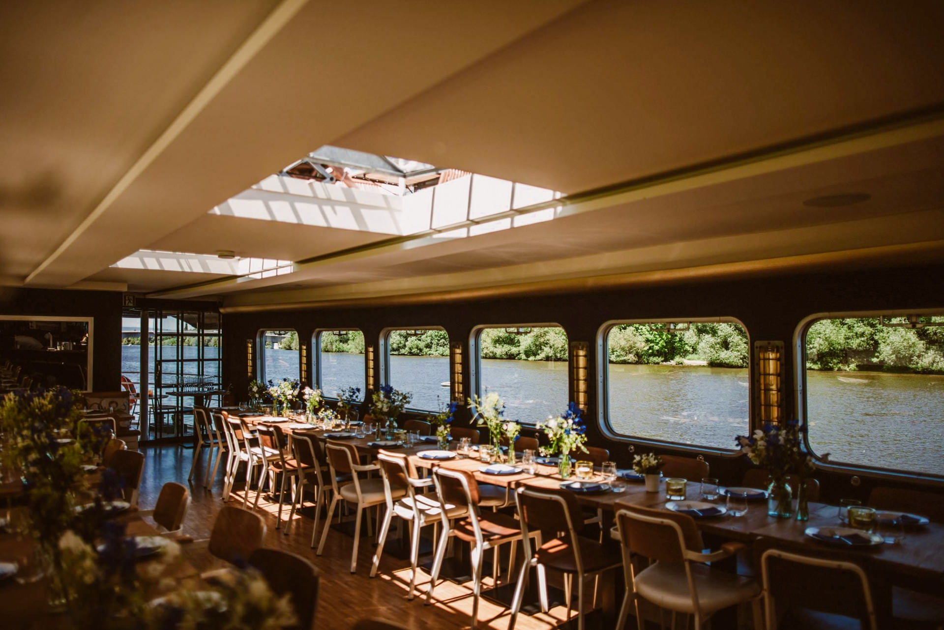 Der Restaurantbereich der Backschaft zeigt lange Tische mit Blick auf den grünen Main.