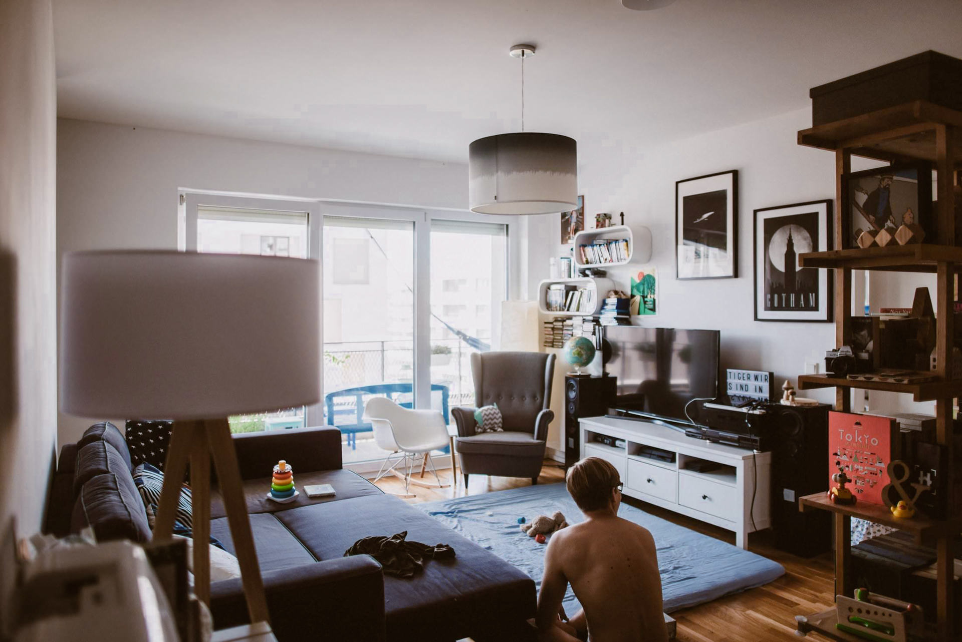 Ein modernes Wohnzimmer zeigt einen Jungen beim Spielen auf einem blauen Teppich.