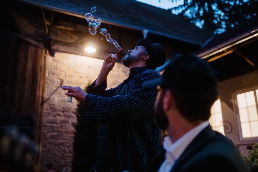Gast pustet abends Seifenblasen bei der Hochzeitsfeier