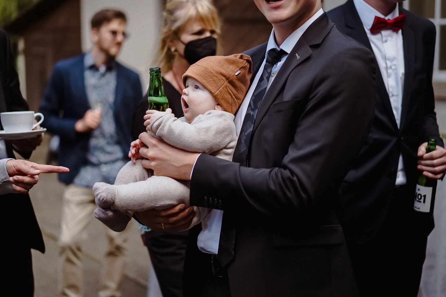 Hochzeitsgast hält ein Baby beim Sektempfang