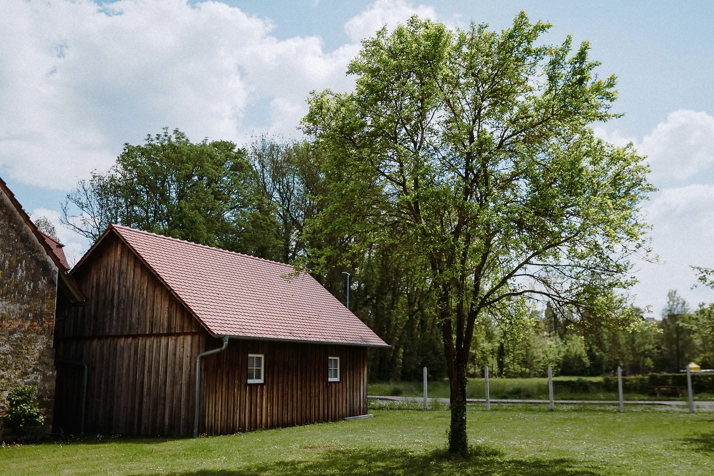 Die historische Scheune der Hochzeitslocation Berthold 57 in Kraichtal mit großem Baum auf der Wiese