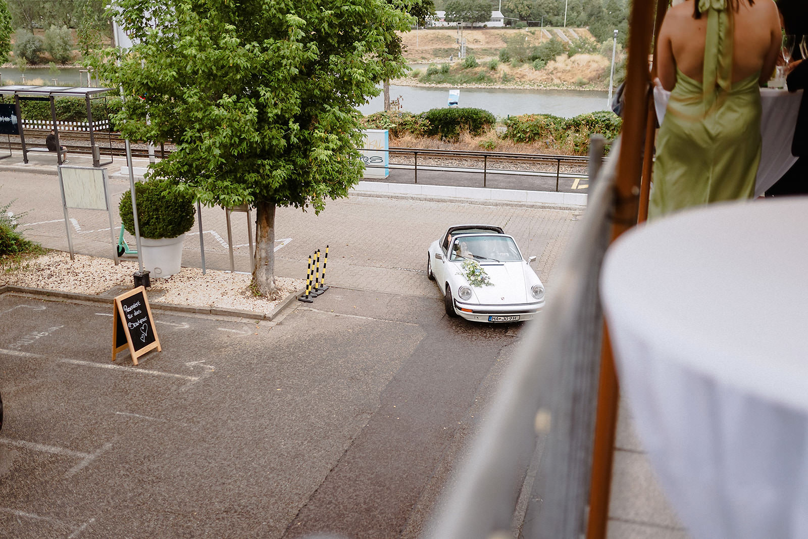 Von der Terrasse aus gesehen: der weiße Porsche parkt vor dem Bootshaus