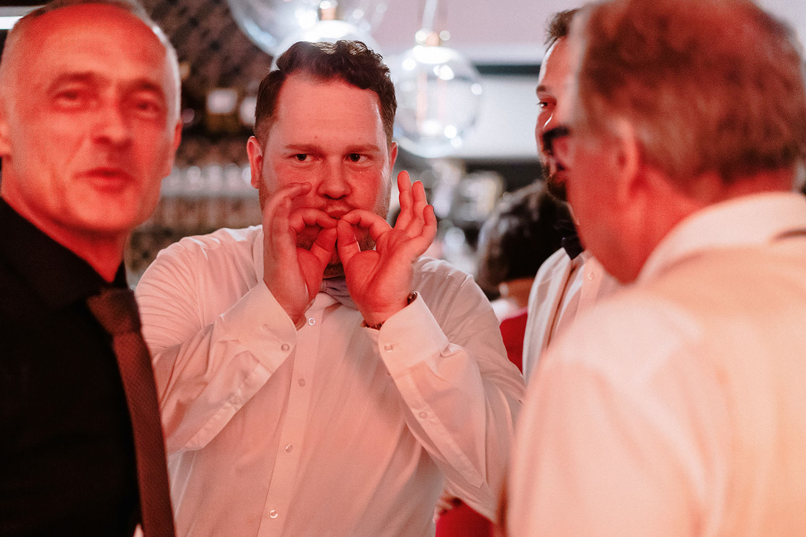 Ein Gast pfeift im roten Partylicht auf den Fingern