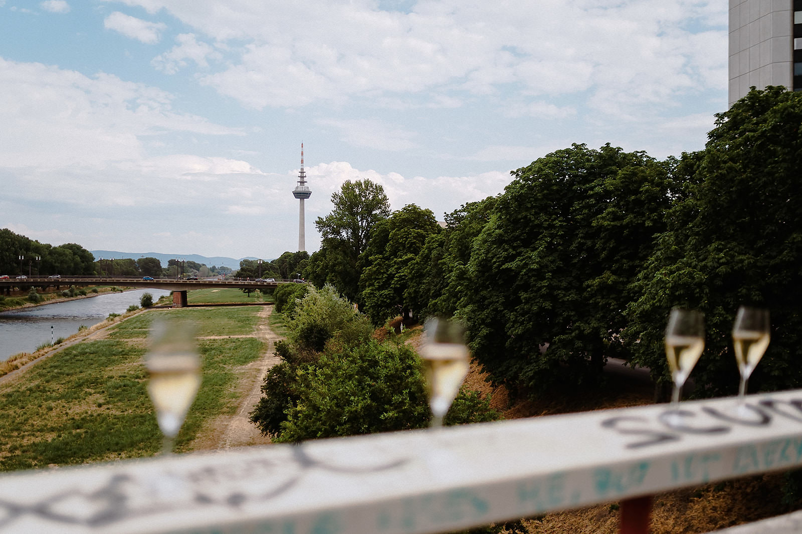Zwei Sektgläser auf dem Brückengeländer, dahinter der Mannheimer Fernsehturm