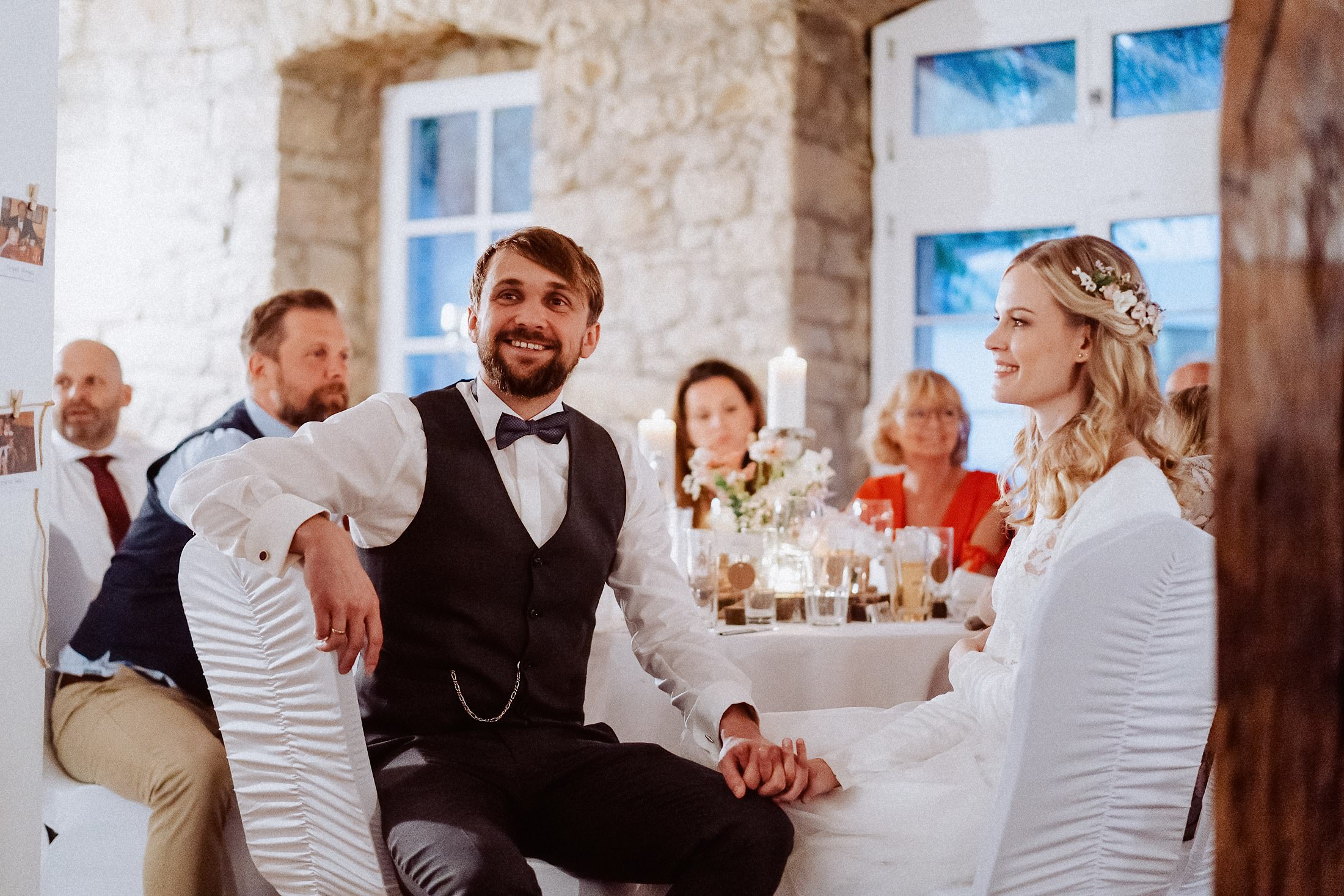 Braut und Bräutigam halten an der Tafel im Bruchsteinsaal die Hände.