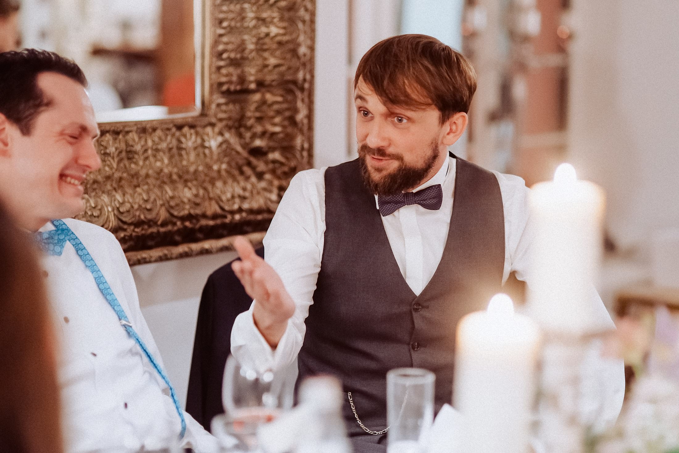 Ein Gast erzählt gestikulierend am festlich gedeckten Tisch mit Kerzen.