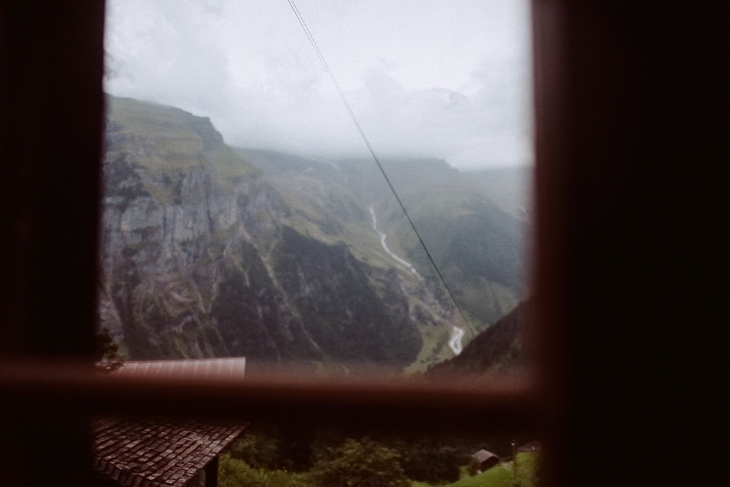 Bergtal-Aussicht durchs Fenster mit Felswand, Wasserlauf.