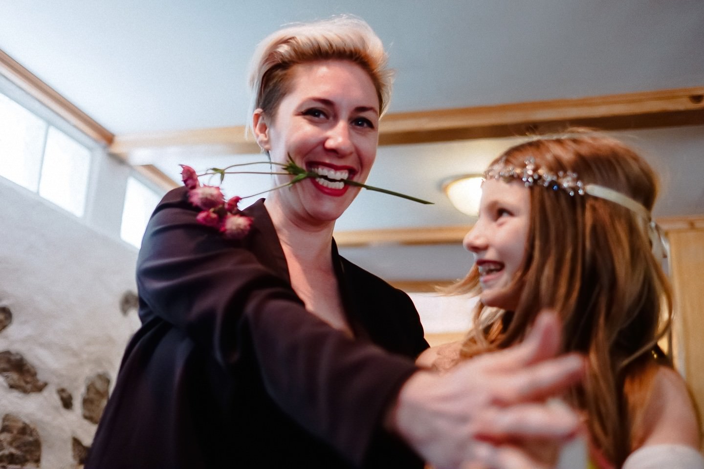 Frau mit Blume im Mund, lachend, verspielte Moment.