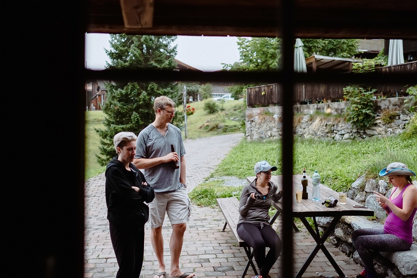 Hochzeitsgäste beim Picknick durchs Holzfenster, entspannt.