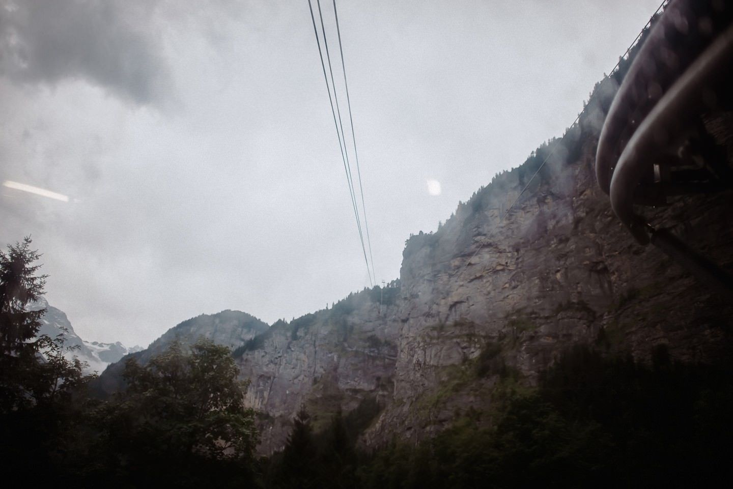 Berggebiet mit Seilbahnkabel und Felswand, Wald.