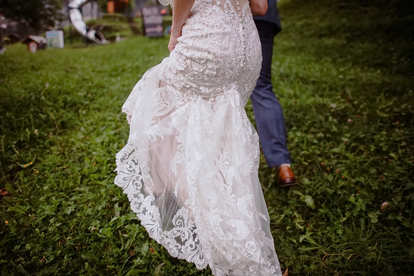 Hochzeitskleid Spitzendetail beim Gehen, Brautpaar im Grünen.