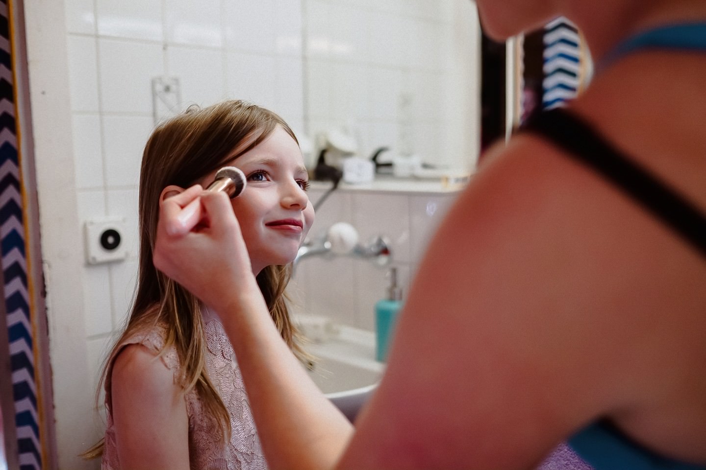 Kleine Tochter wird geschminkt, lächelt, freudiger Moment.
