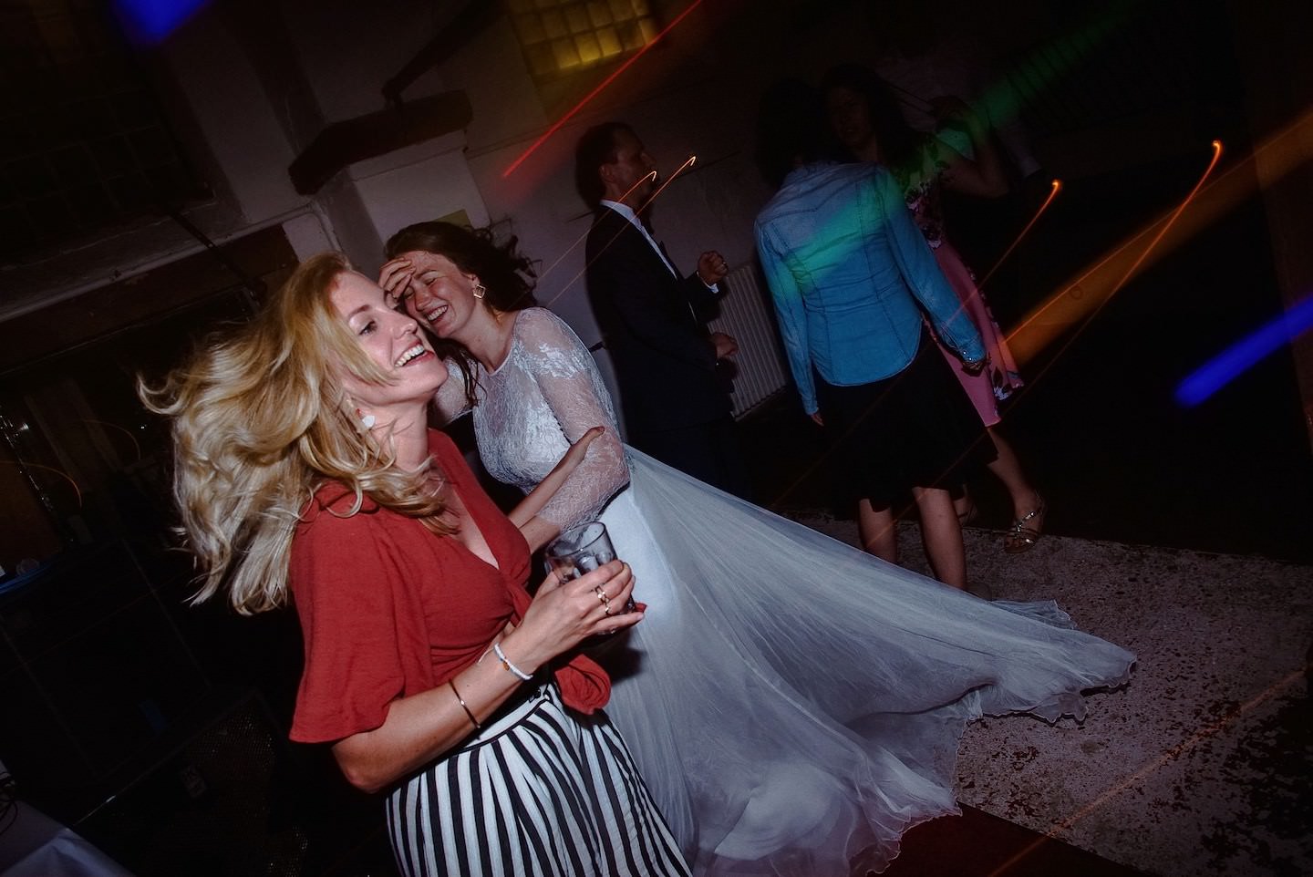 Braut und Gast tanzen auf Tanzfläche mit bunten Laser-Lichtern, Nacht-Party.