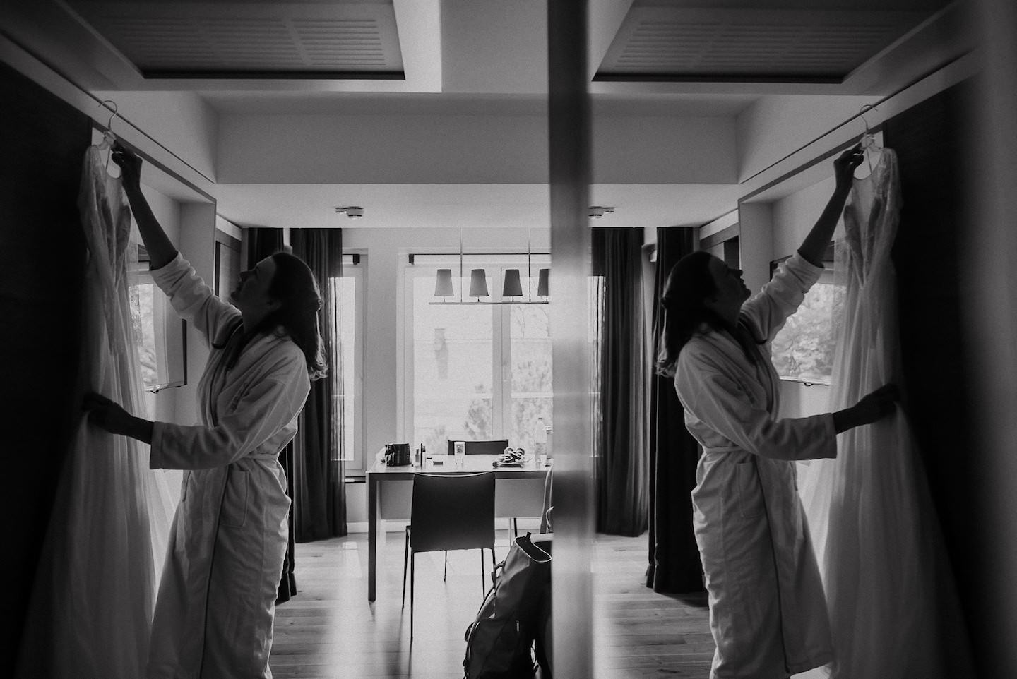 Braut-Spiegelbild hält Kleid, Hotelzimmer, schwarz-weiß, symmetrisch, Fertigmachen.