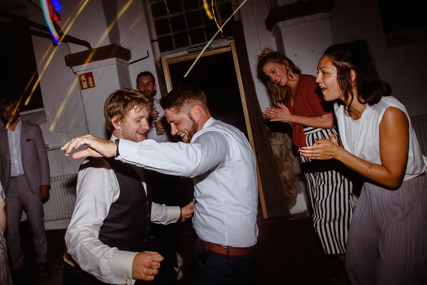 Gäste tanzen eng zusammen im Innenhof mit Laserlicht-Show, lustige Party-Stimmung.