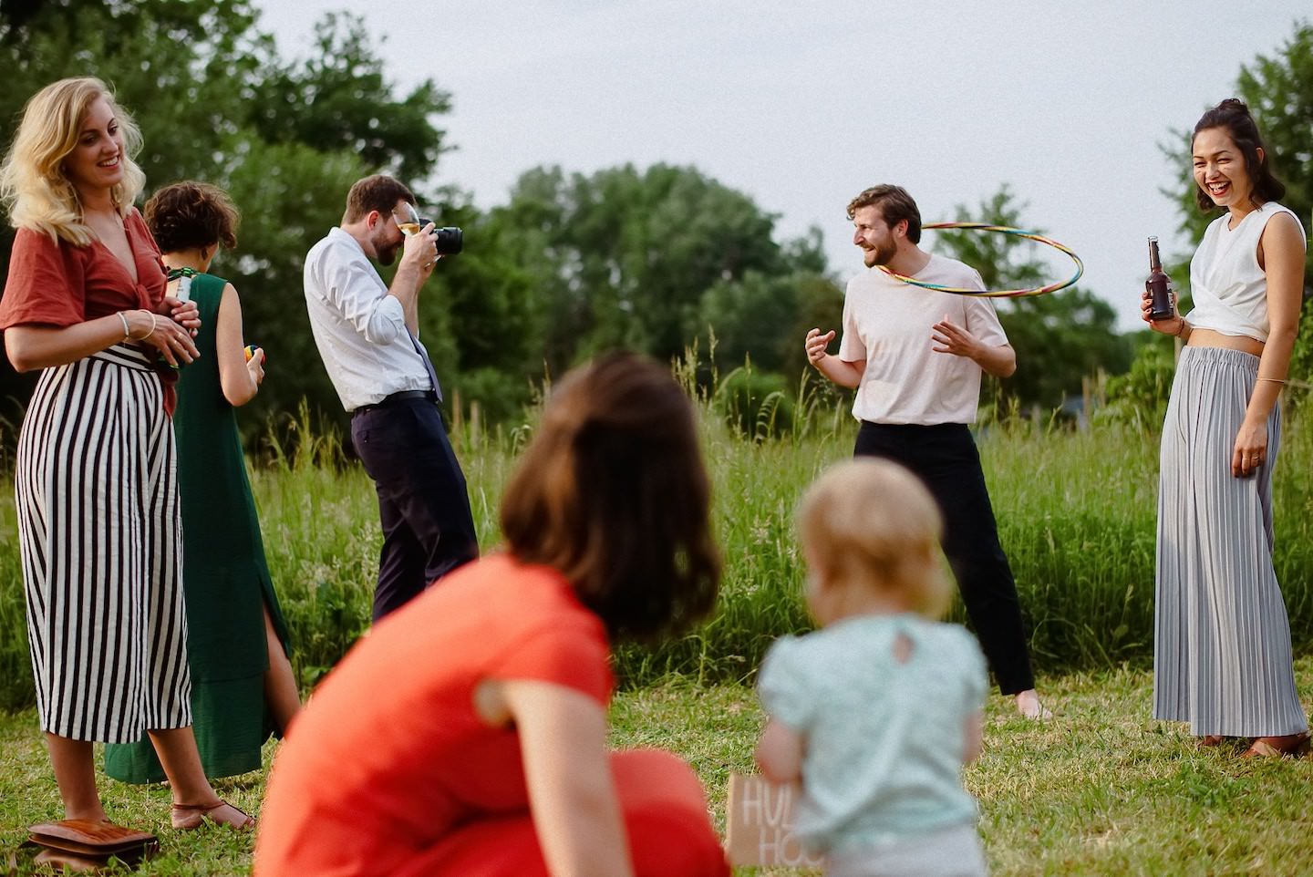 Hochzeitsgäste spielen Hula-Hoop auf Rasen, mehrere aktiv, lustige Spielatmosphäre.