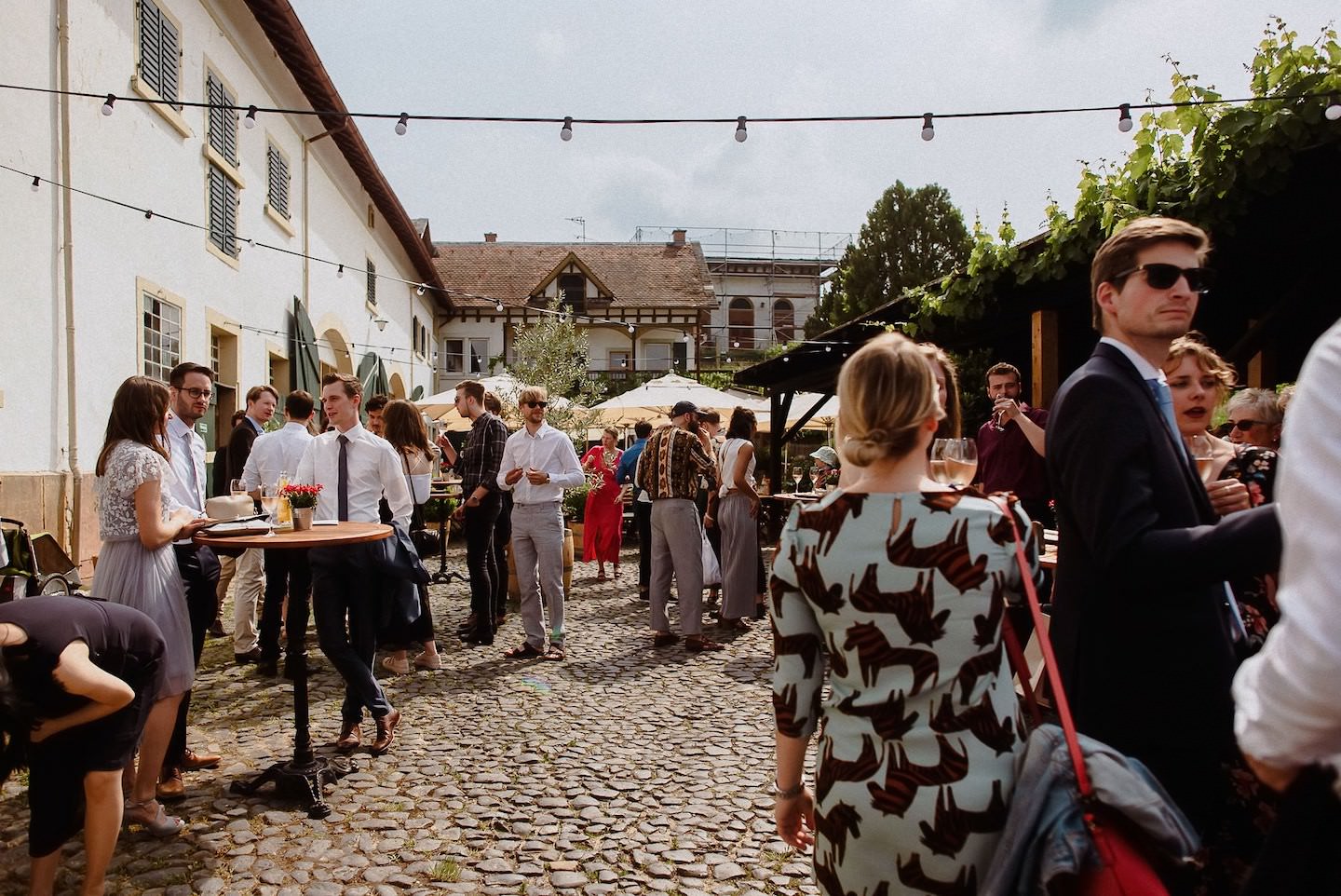 Innenhof Hochzeitsempfang, Hofgut, String-Lichter, Gäste, Wein, Tische.