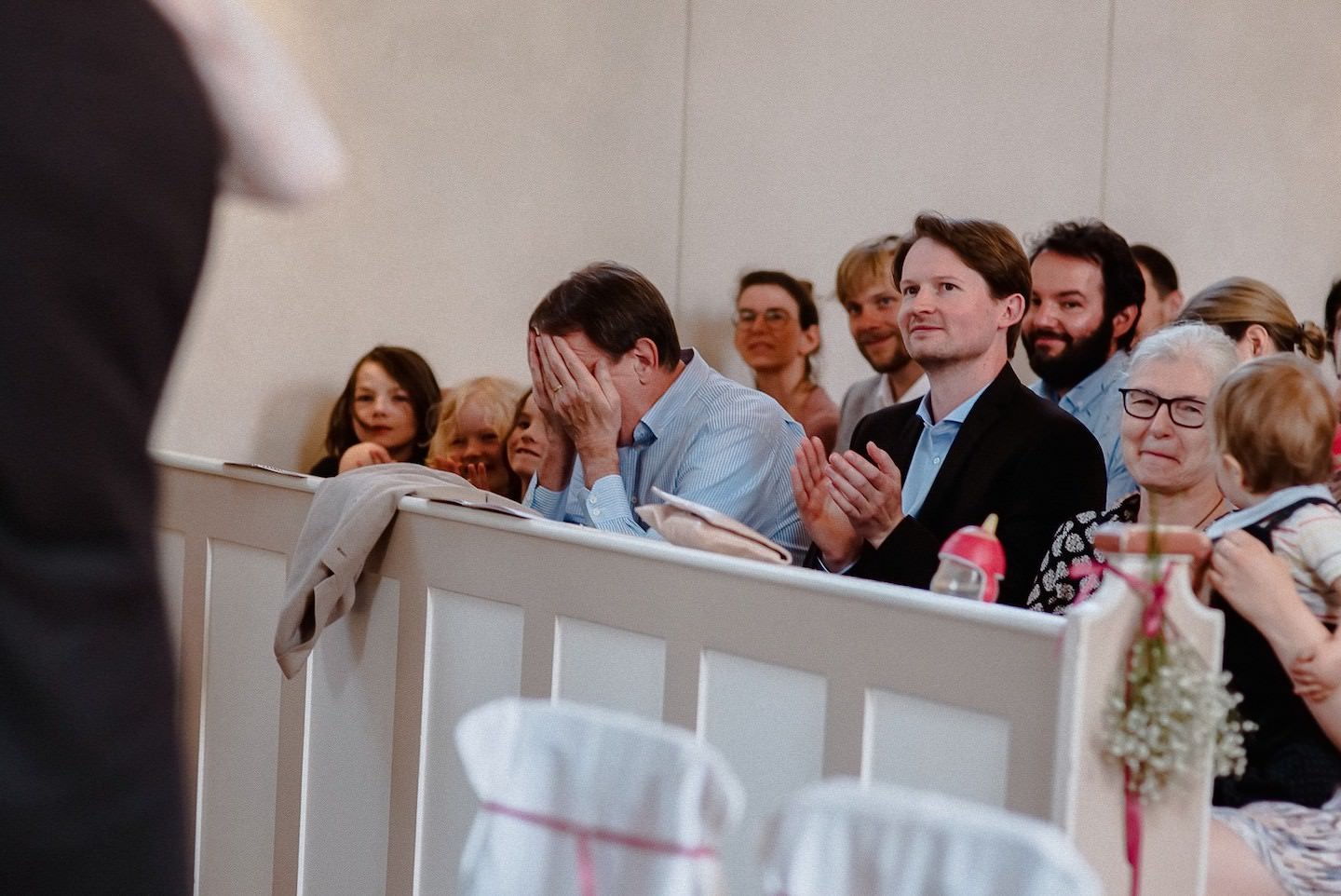 Hochzeitsgäste während Trauung in Kirche, einige müde, gespannte Aufmerksamkeit.