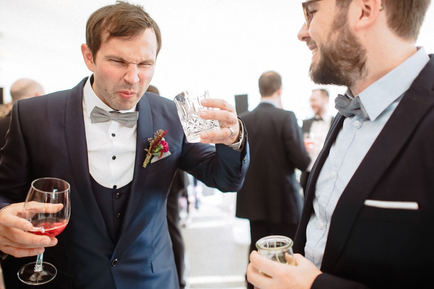 Bräutigam mit Drink-Glas neben Gast, Sektempfang.