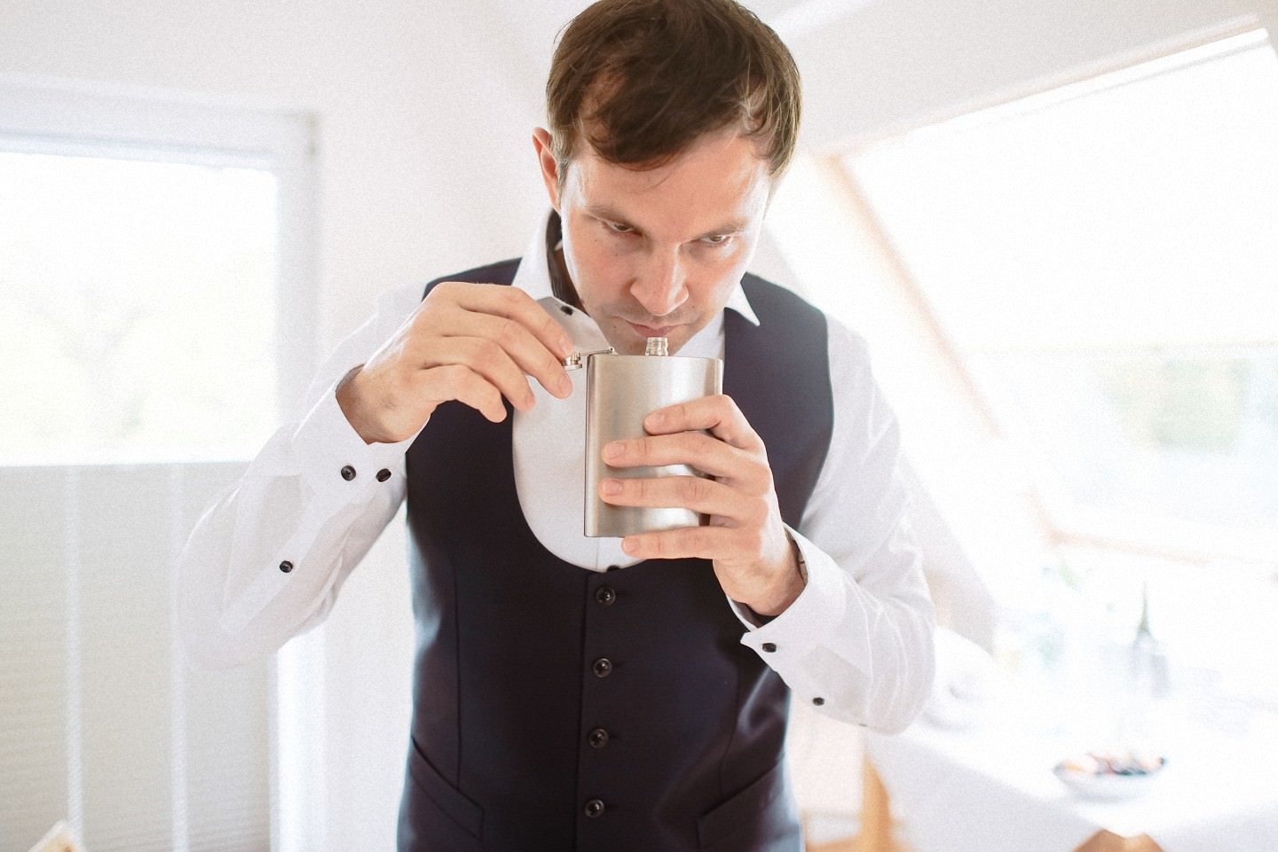Bräutigam in anderer Pose mit Flachmann beim Schnaps-Ritual.