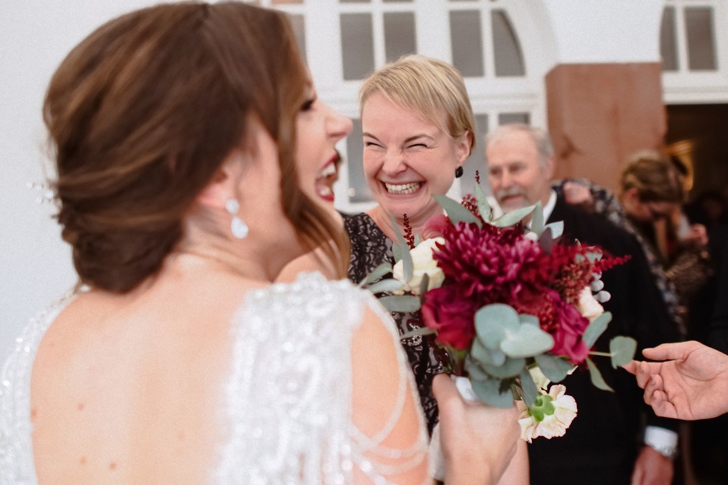 Braut lacht mit Gast während Gratulationen, frohe Stimmung.