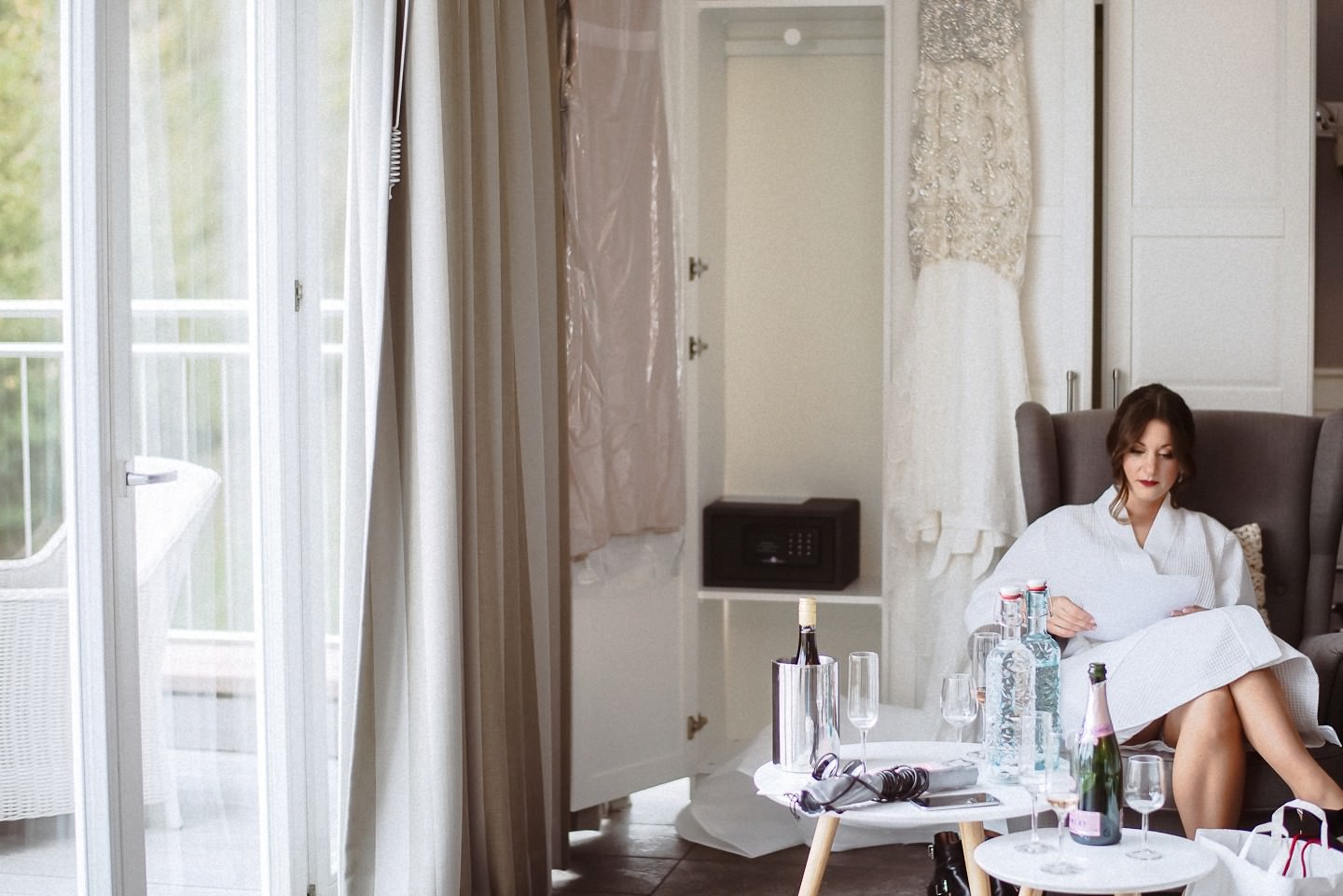 Braut in weißem Seidenmantel liest Brief sitzend, Hotelzimmer.