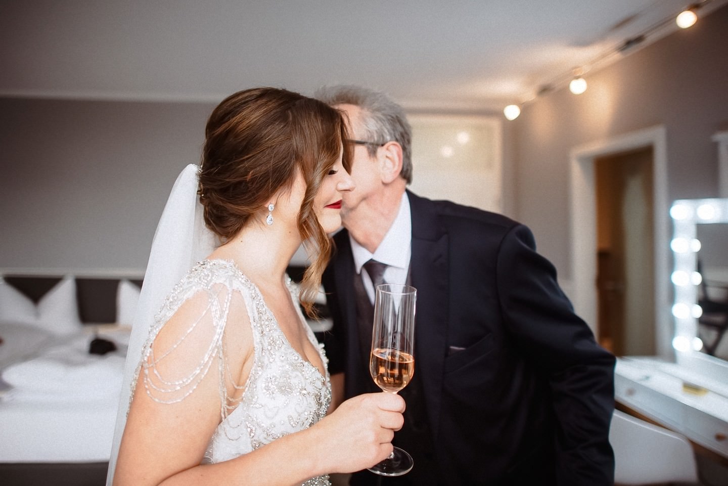 Braut + Vater mit Sekt-Gläsern beim feierlichen Moment.