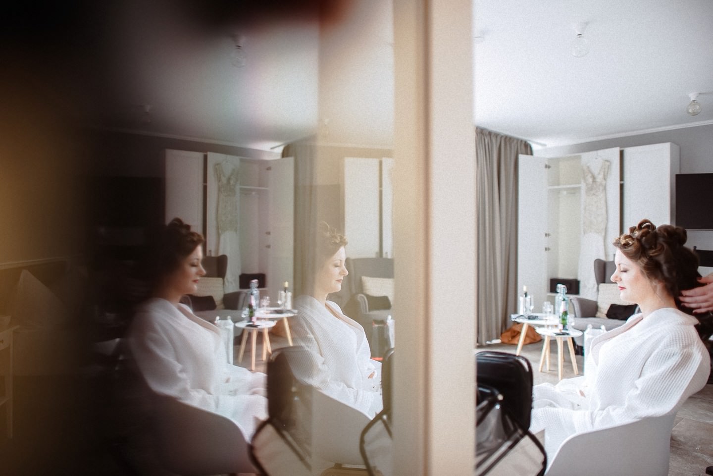 Spiegelbild im Hotelzimmer zeigt Braut + Trauzeuginnen in weiß.