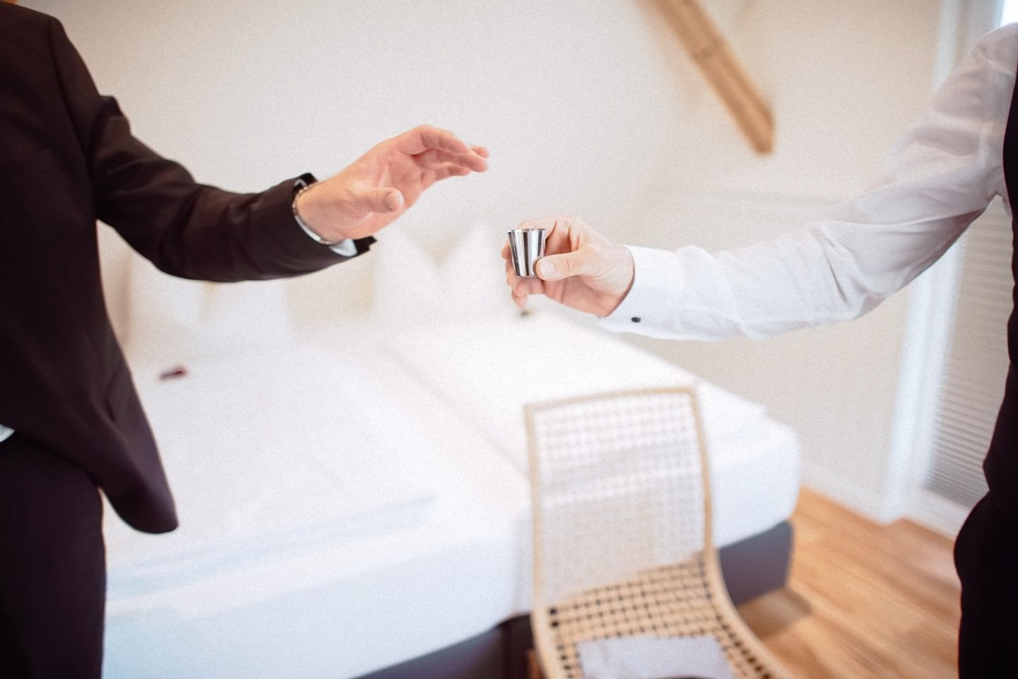 Zwei Männer stoßen mit Schnaps-Gläsern an Tisch an.