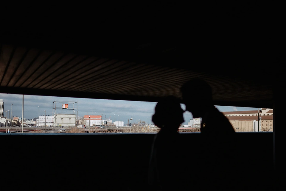 Brautpaar küsst sich als Silhouette unter einem Vordach mit Blick auf die Skyline.