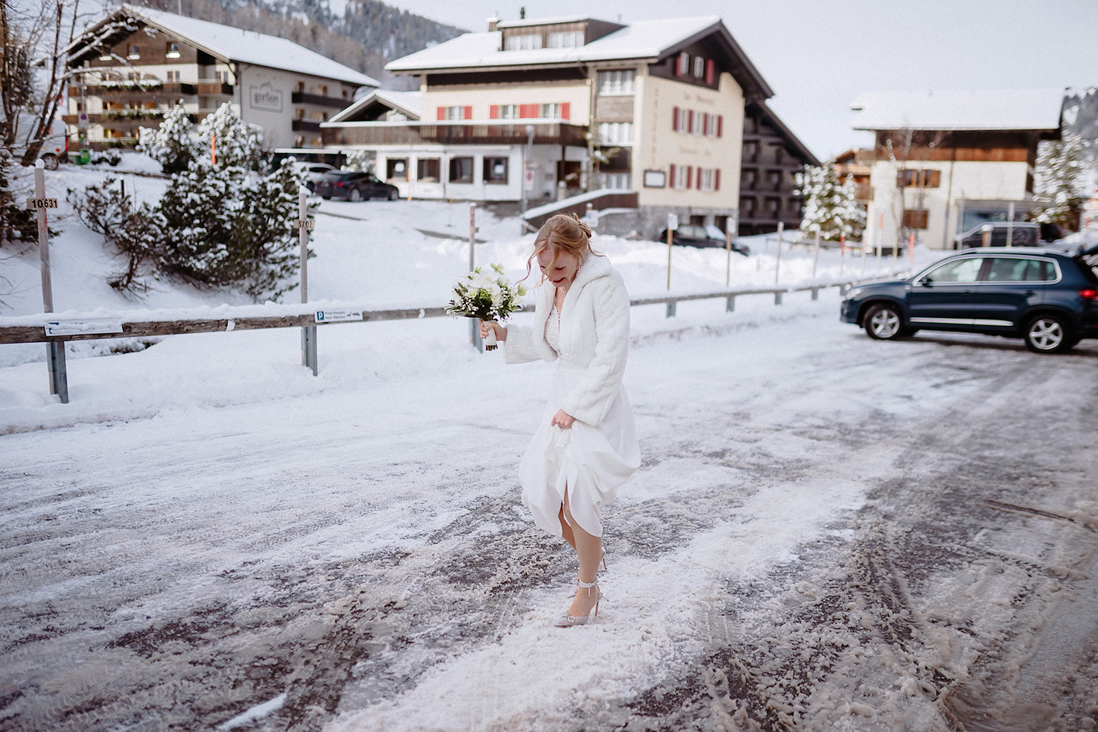 Die Braut steht mit ihrem Strauß im tiefen Schnee von Malbun in Liechtenstein