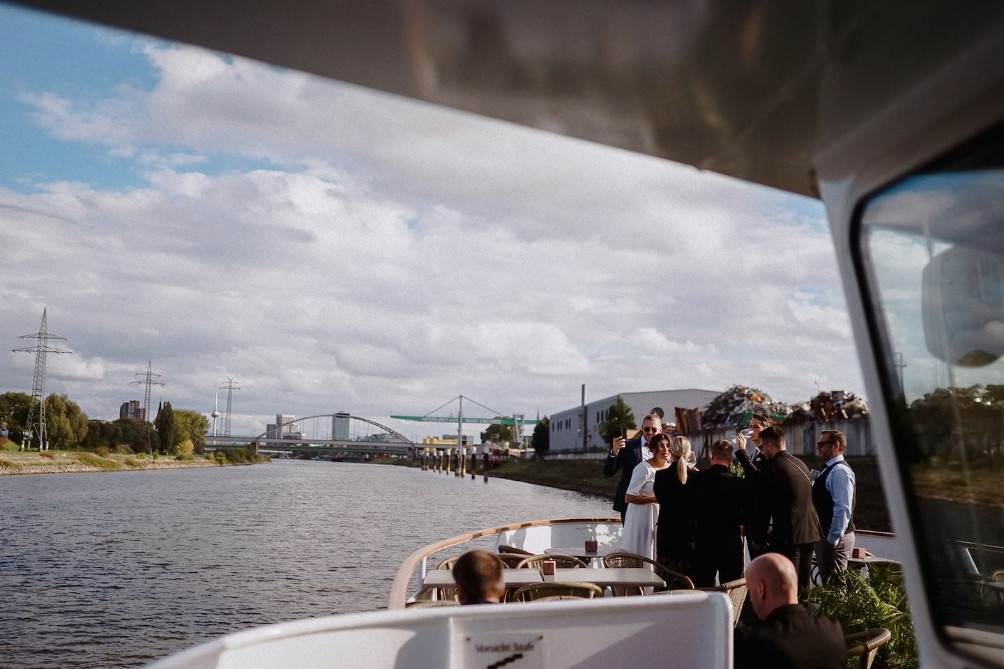 Hochzeitsgäste stehen unter dem Schiffsdach an Deck