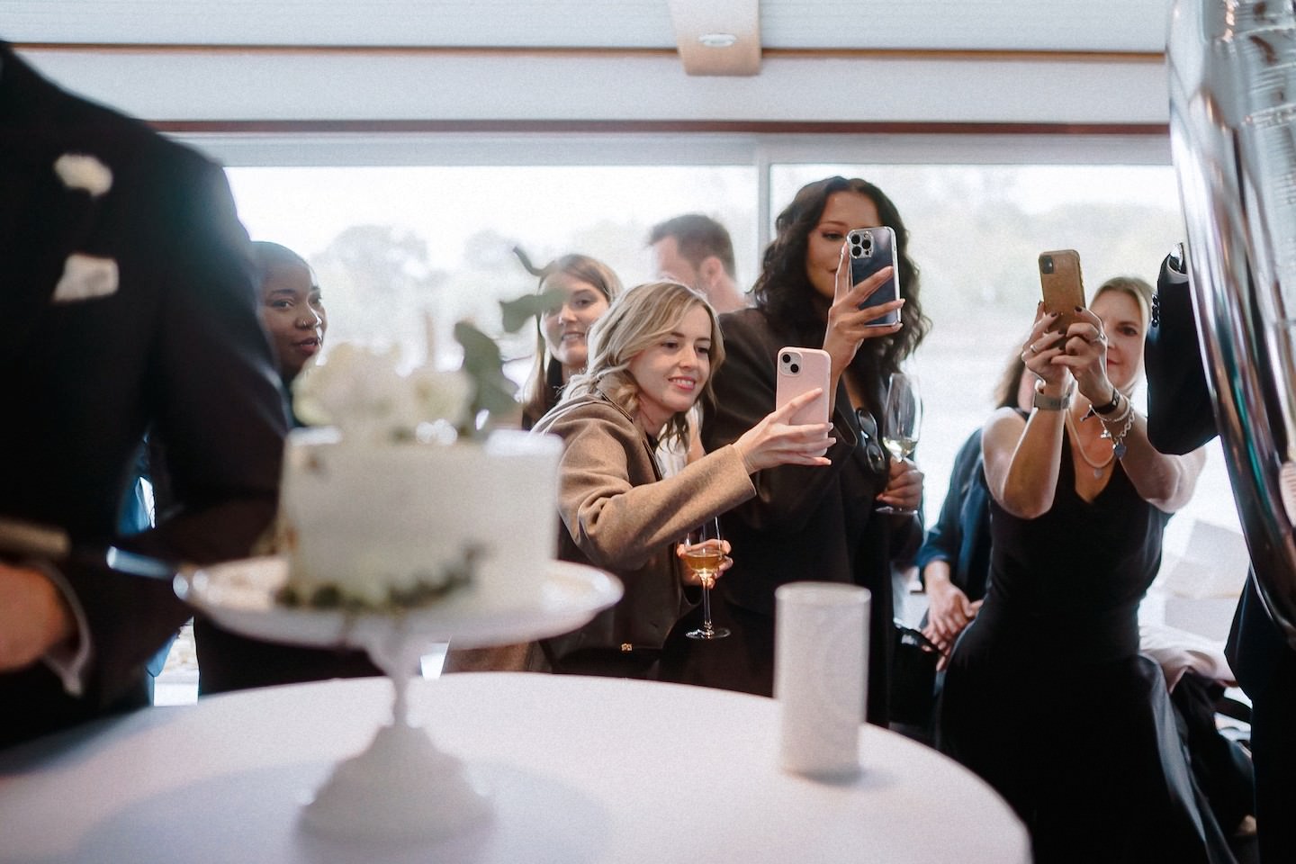 Gäste fotografieren die Hochzeitstorte mit ihren Smartphones