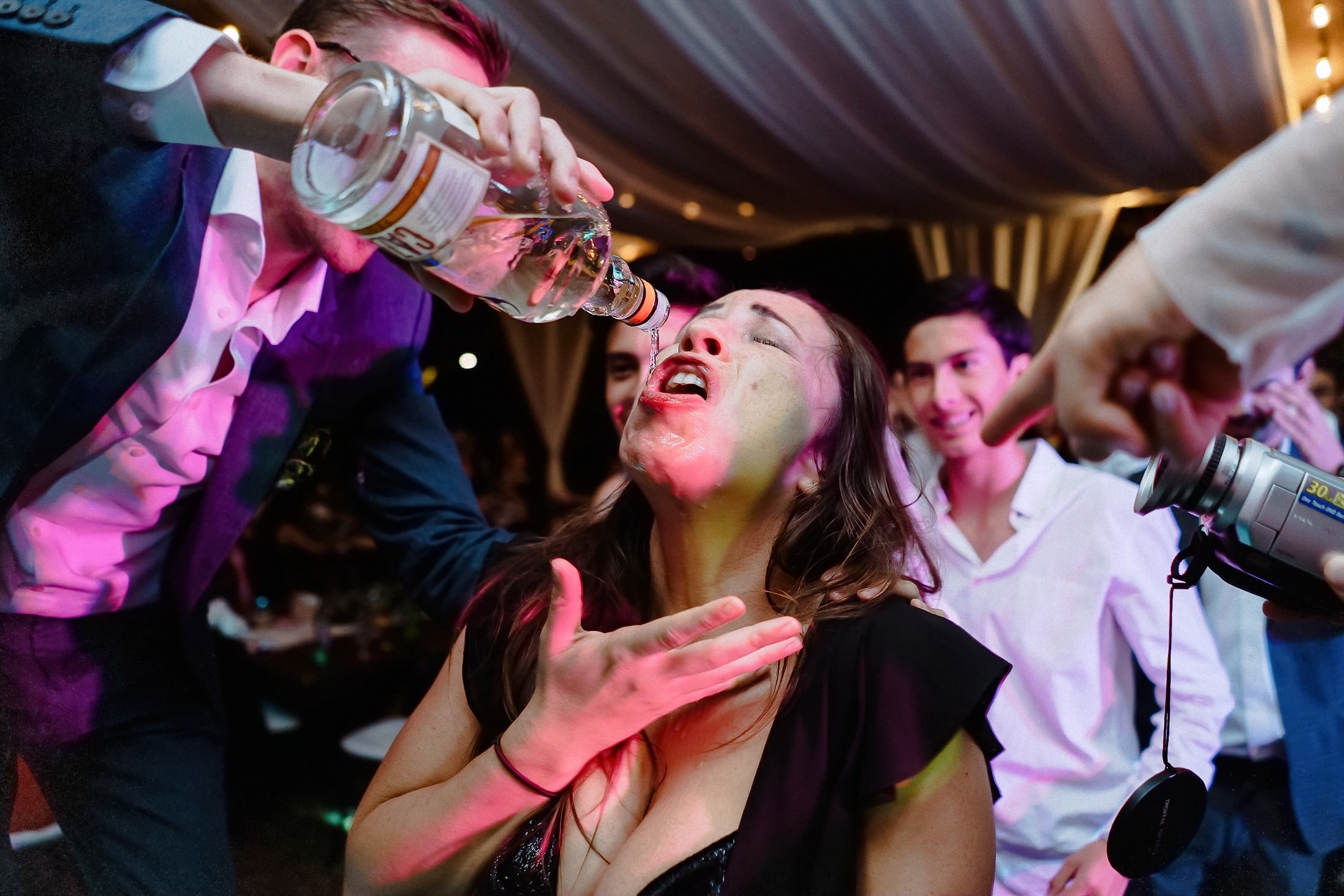 Ein Gast trinkt Mezcal nach hinten geworfen, zwei weitere Hände halten Flaschen fest