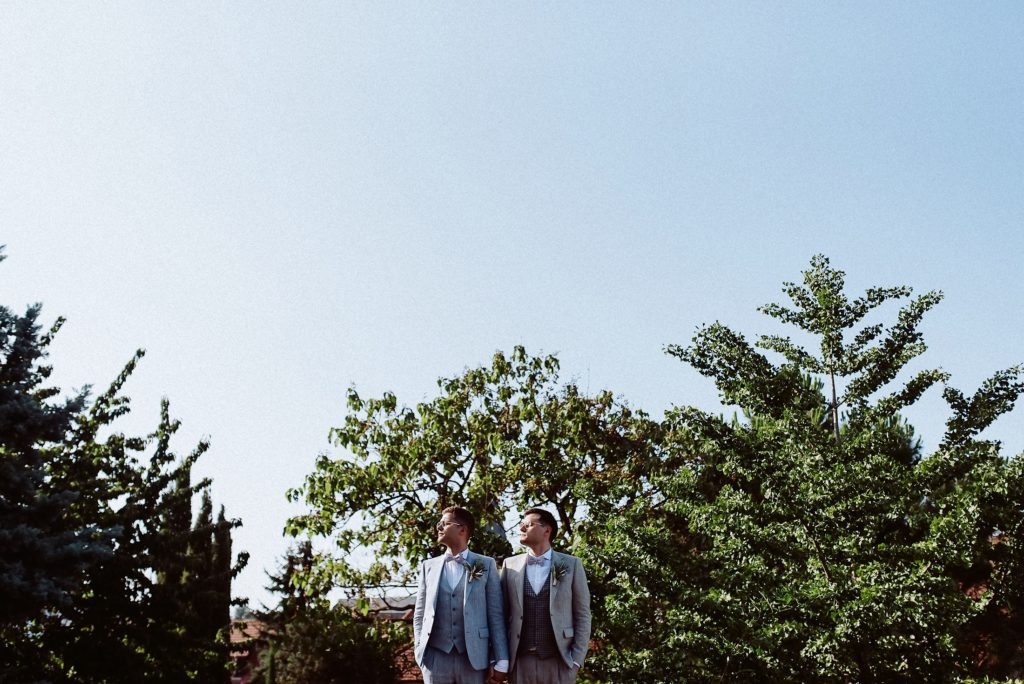 Hochzeitsfotografie-Moment mit beiden Bräutigamen im Garten.