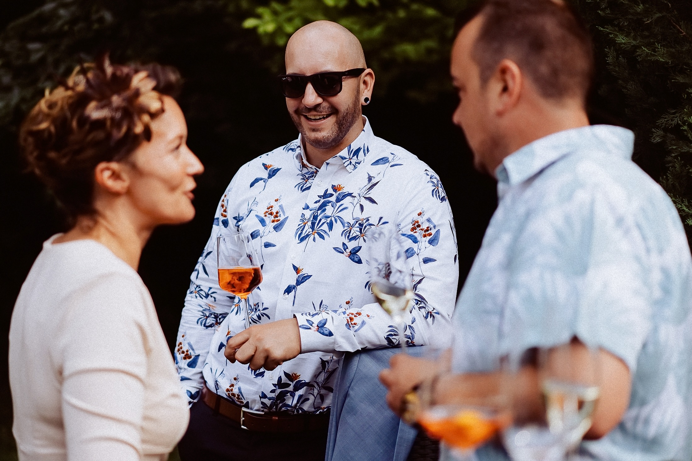 Gäste haben Spaß, lachen mit Sektgläsern im Garten.