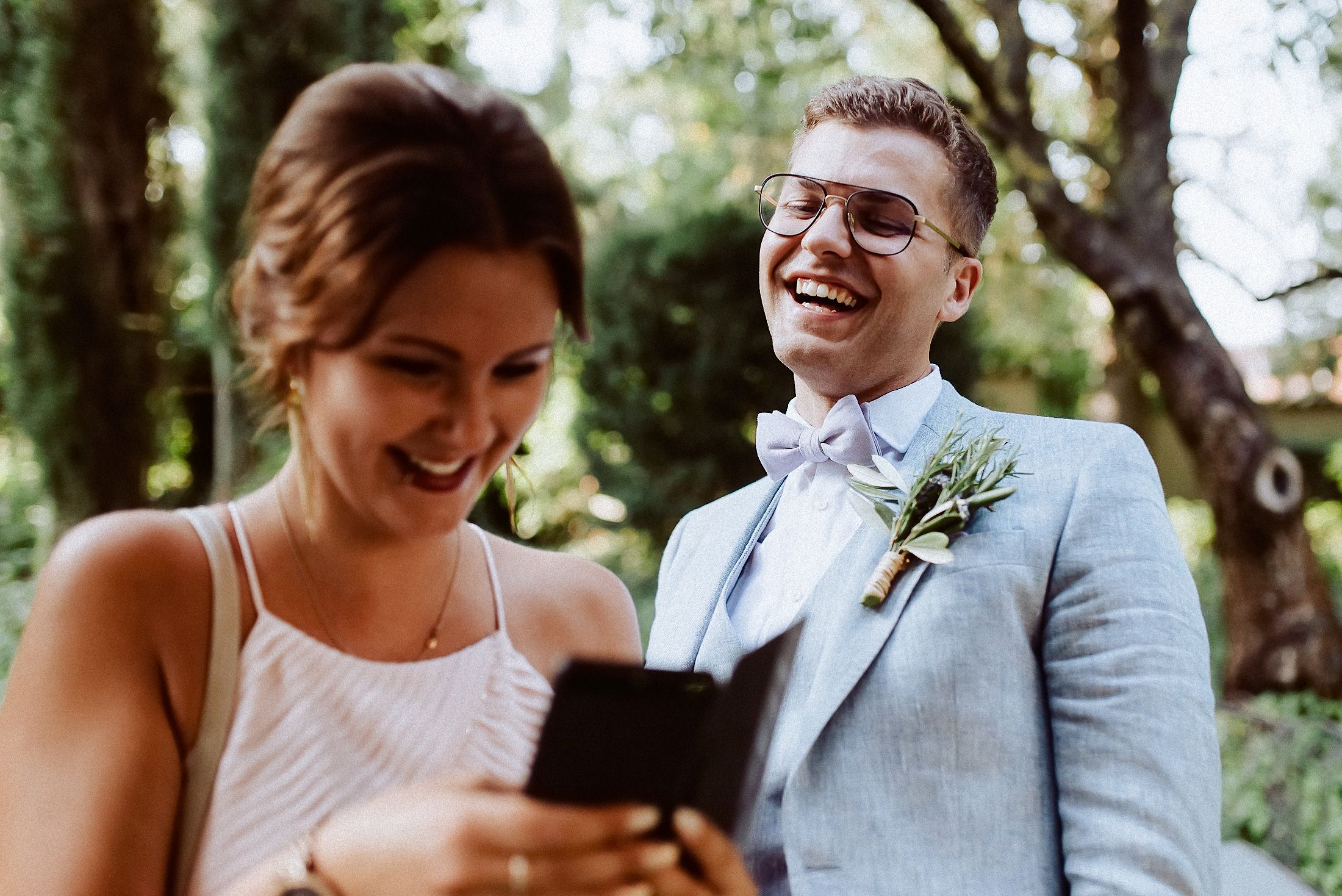 Hochzeitsgast macht Selfie mit einem der Bräutigame lachend.