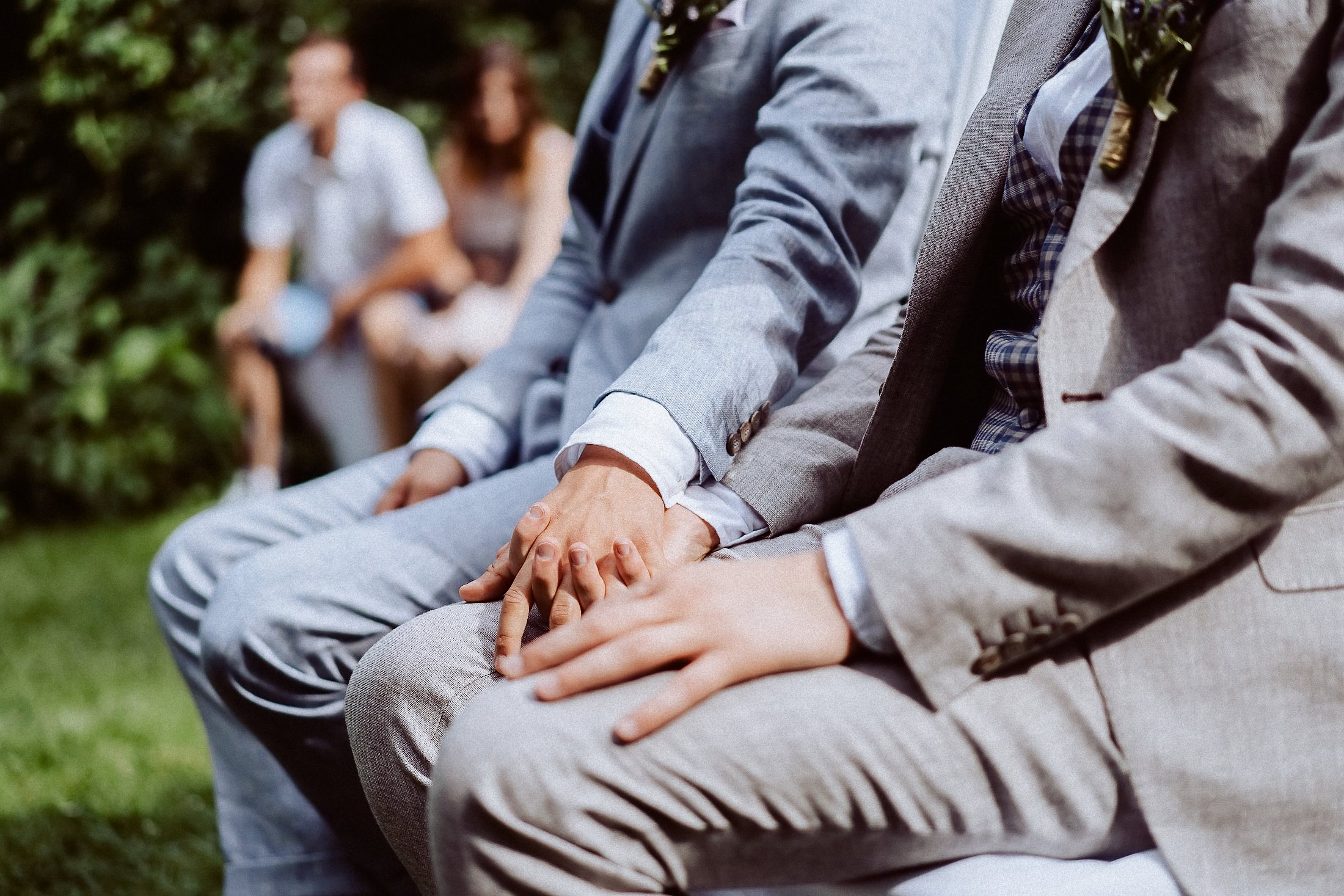 Zwei Männer in Anzügen mit Boutonnieres stehen zusammen bei Trauung.