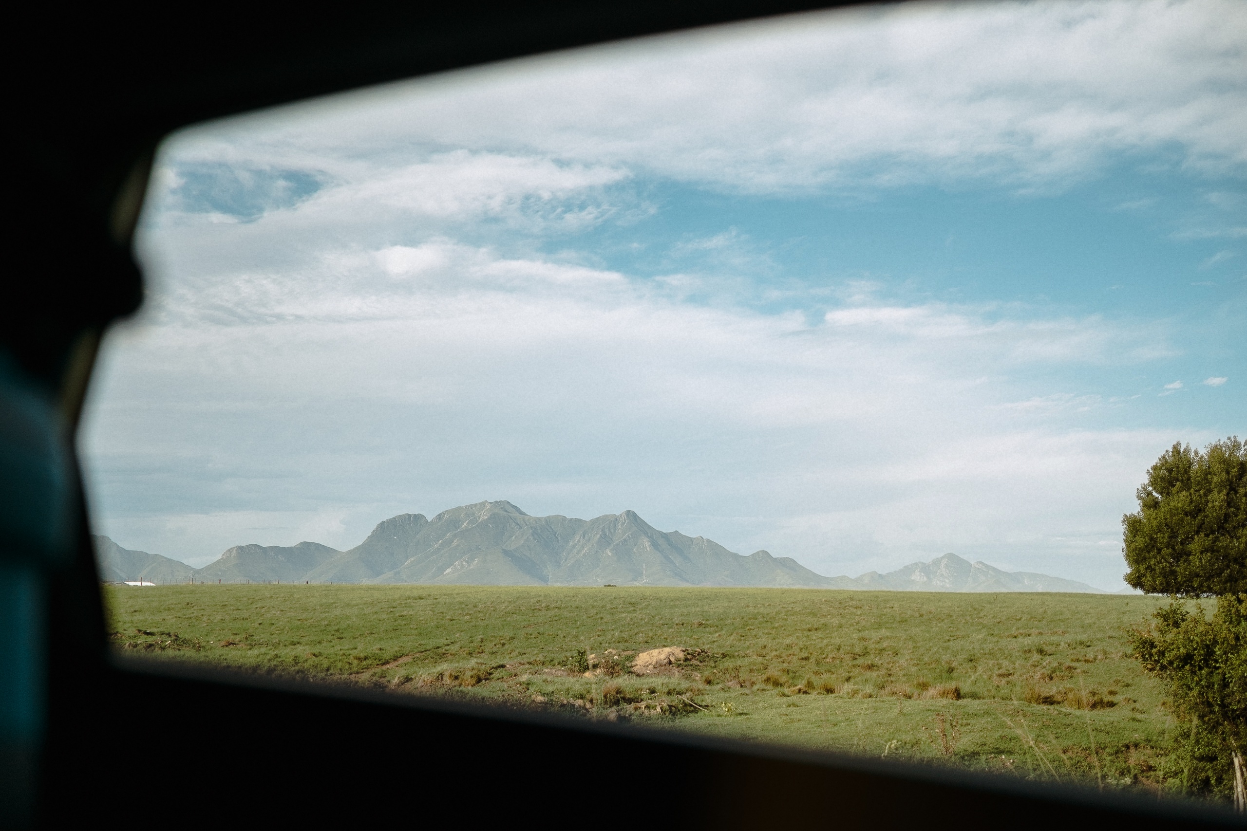 Weideland und Bergkette hinter der Kante des Autofensters auf dem Weg nach Mossel Bay