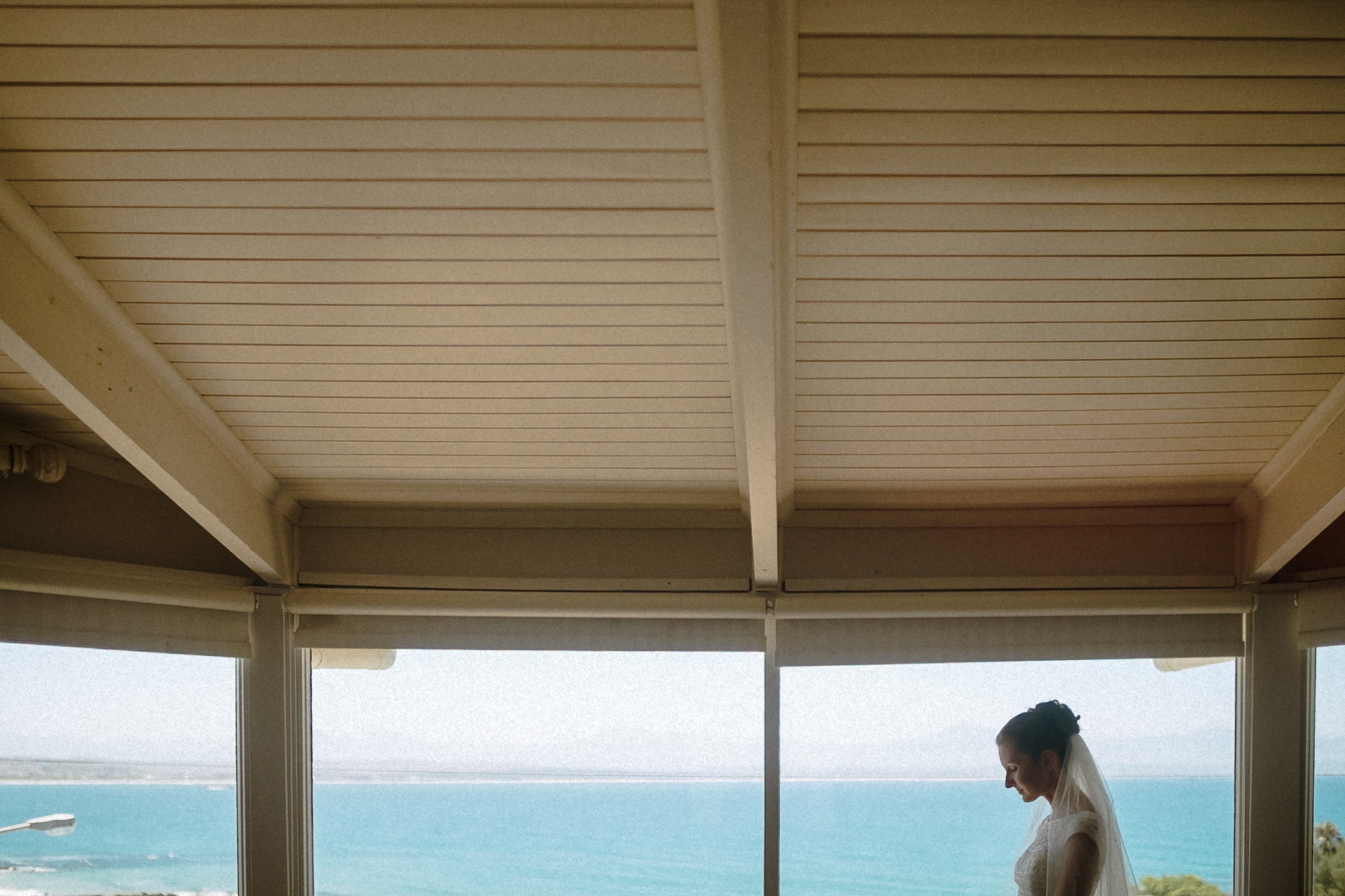 Die Braut steht am Fenster, dahinter die Bucht von Mossel Bay